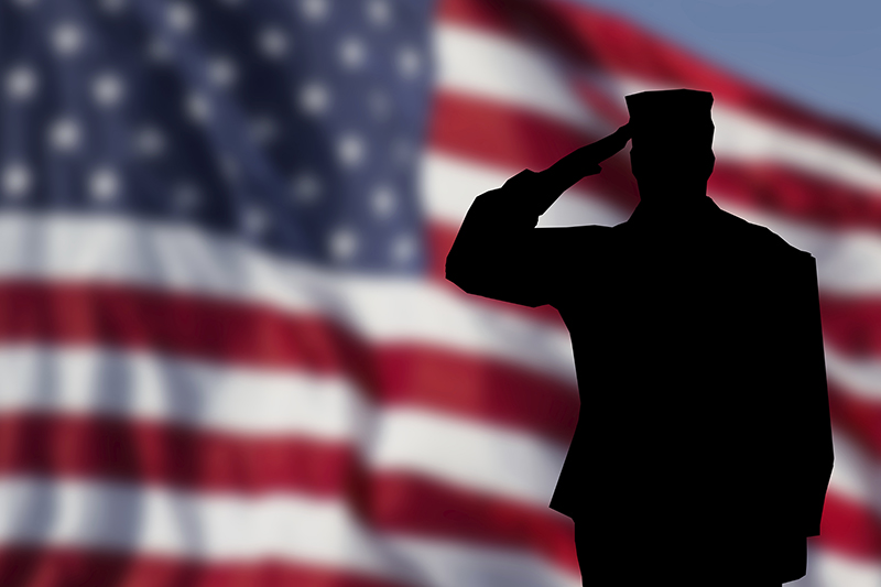 Military member saluting with an American flag in the background