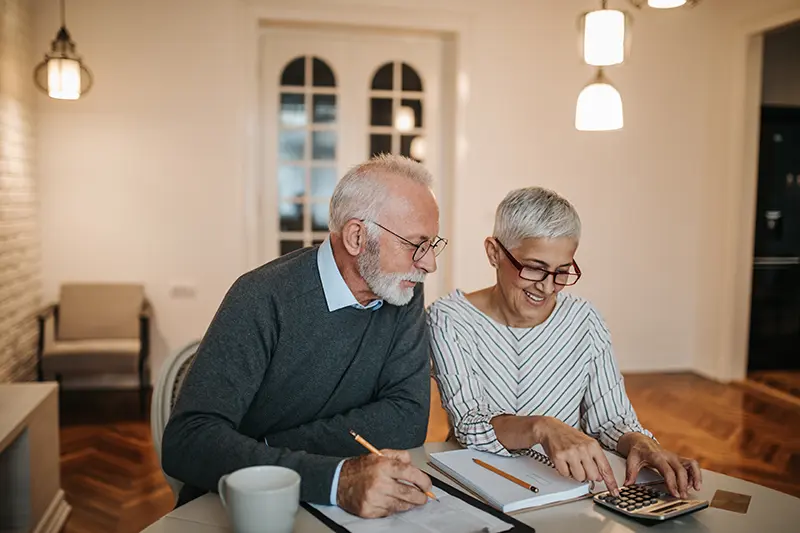 An older couple looking at a calculator and taking notes