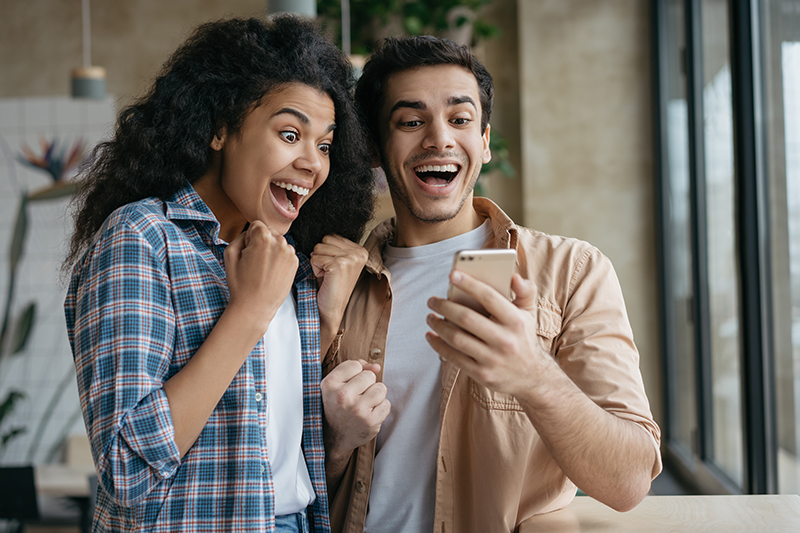 A man and a woman looking at a phone excitedly