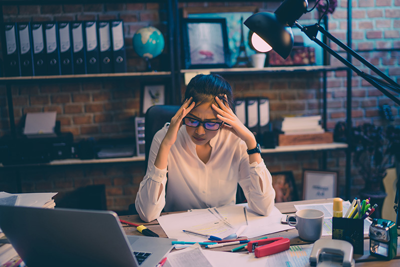 Woman sitting at desk looking frustrated due to a business loss